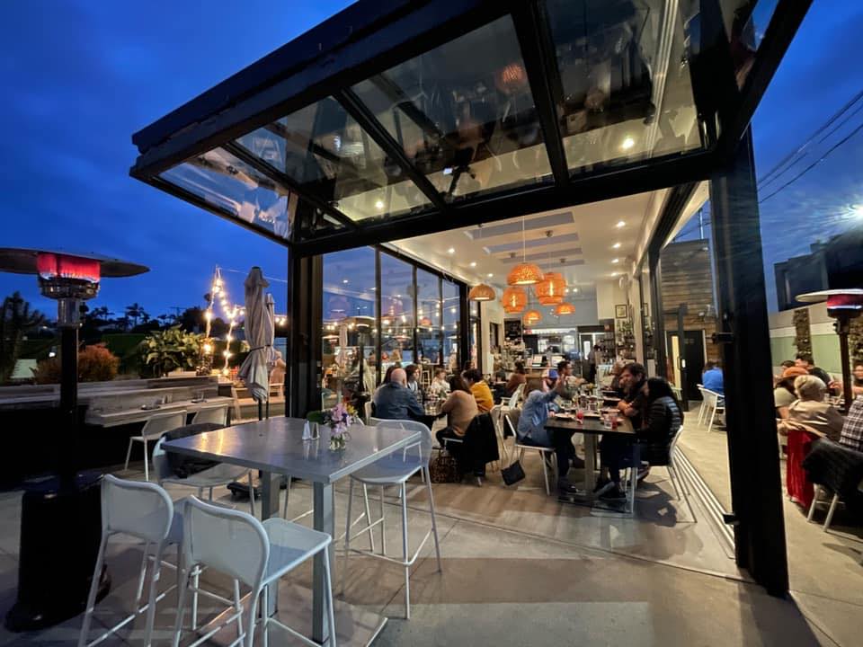 outdoor restaurant space open dining with heat lamps and large windows